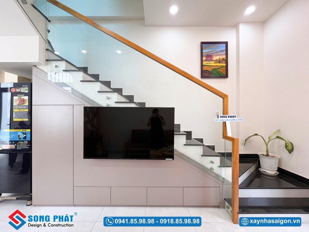 Hệ tủ tivi được thiết kế tinh gọn dưới gầm cầu thang, tối ưu diện tích và tạo sự liền mạch cho phòng khách
