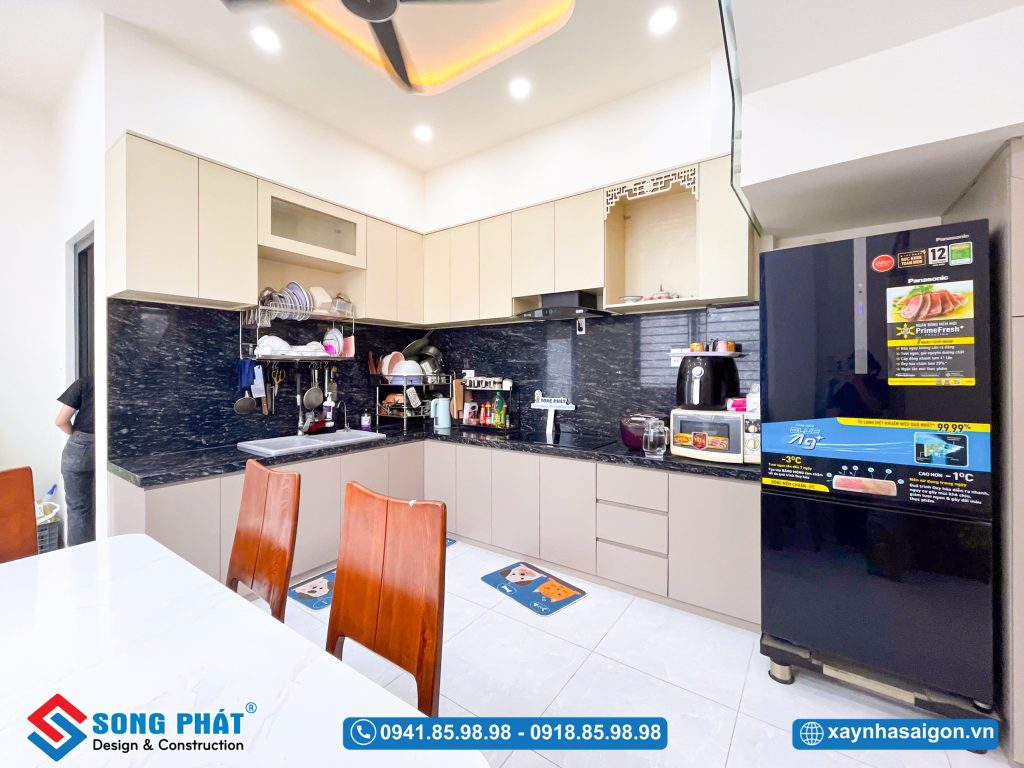 Hệ tủ bếp chữ L hiện đại, với sự kết hợp hài hòa giữa tone màu trung tính và mặt đá đen sang trọng