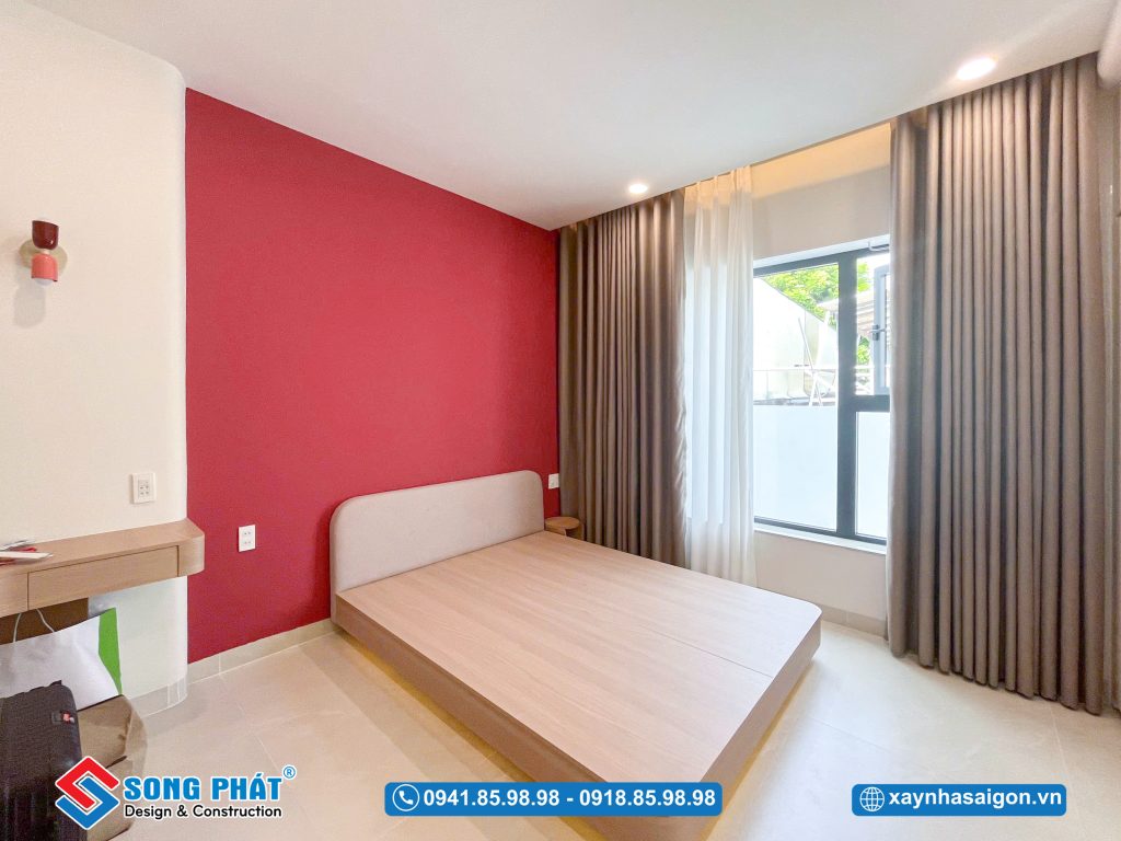 Phòng ngủ với tone đỏ bố trí gọn gàng, ánh sáng hài hòa, tạo cảm giác dễ chịu khi nghỉ ngơi