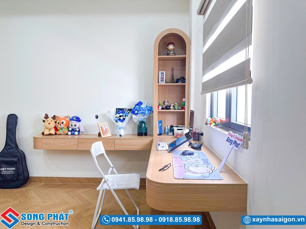 Bàn học góc chữ L liền kề tủ sách vòm độc đáo.