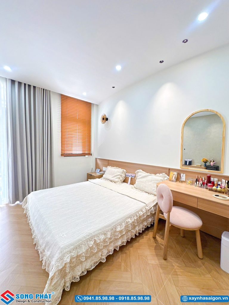 Bàn trang điểm liền kề giường ngủ với gương soi vòm gỗ.