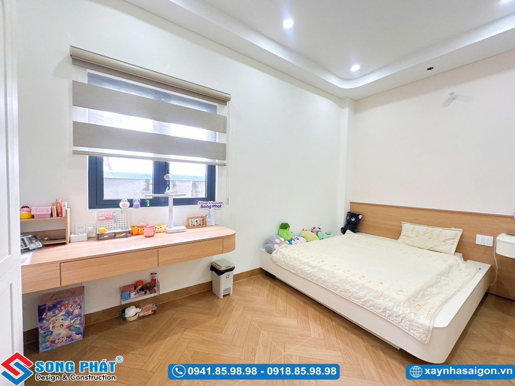 Bàn học treo tường dài cạnh cửa sổ kết hợp rèm cầu vồng.