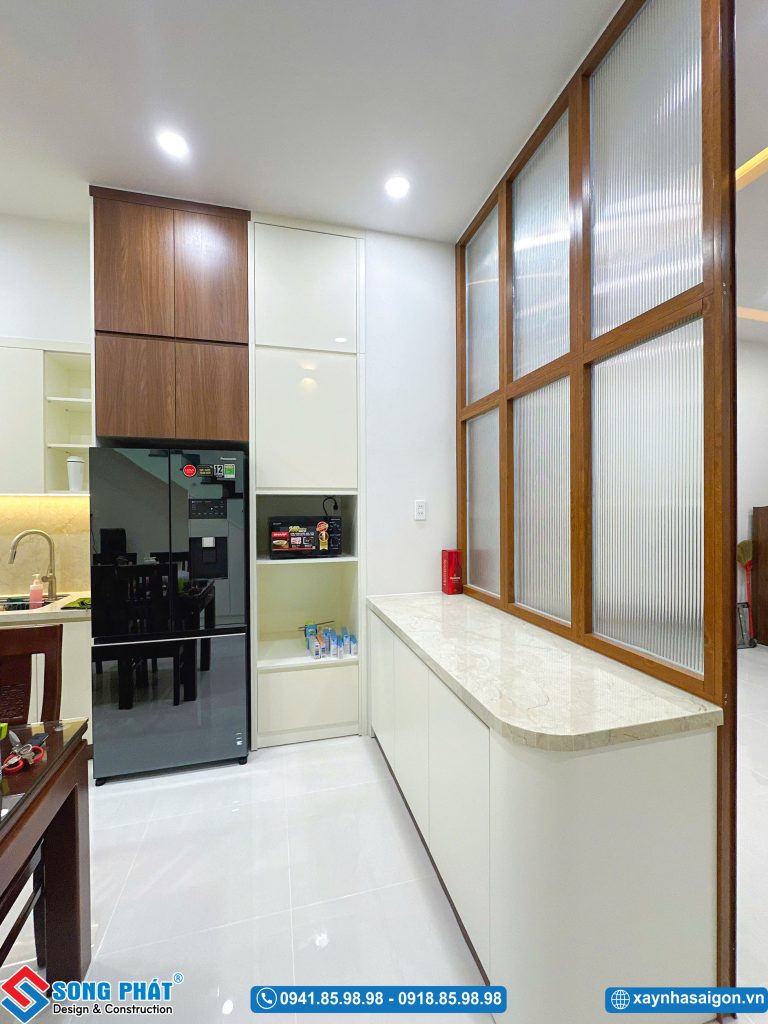Khu vực tủ bếp kết hợp tủ lạnh và tủ kho lưu trữ cao kịch trần, bố trí gọn gàng cạnh vách ngăn.