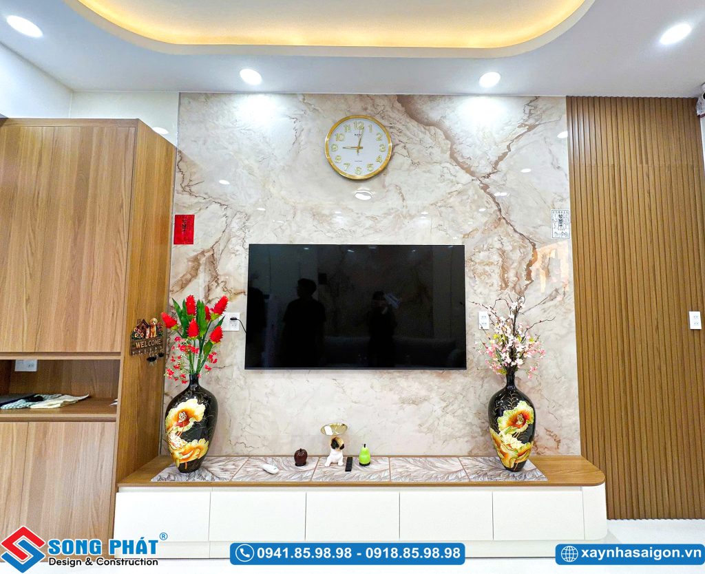 Kệ tivi treo tường kết hợp vách đá hoa cương và lam gỗ trang trí.