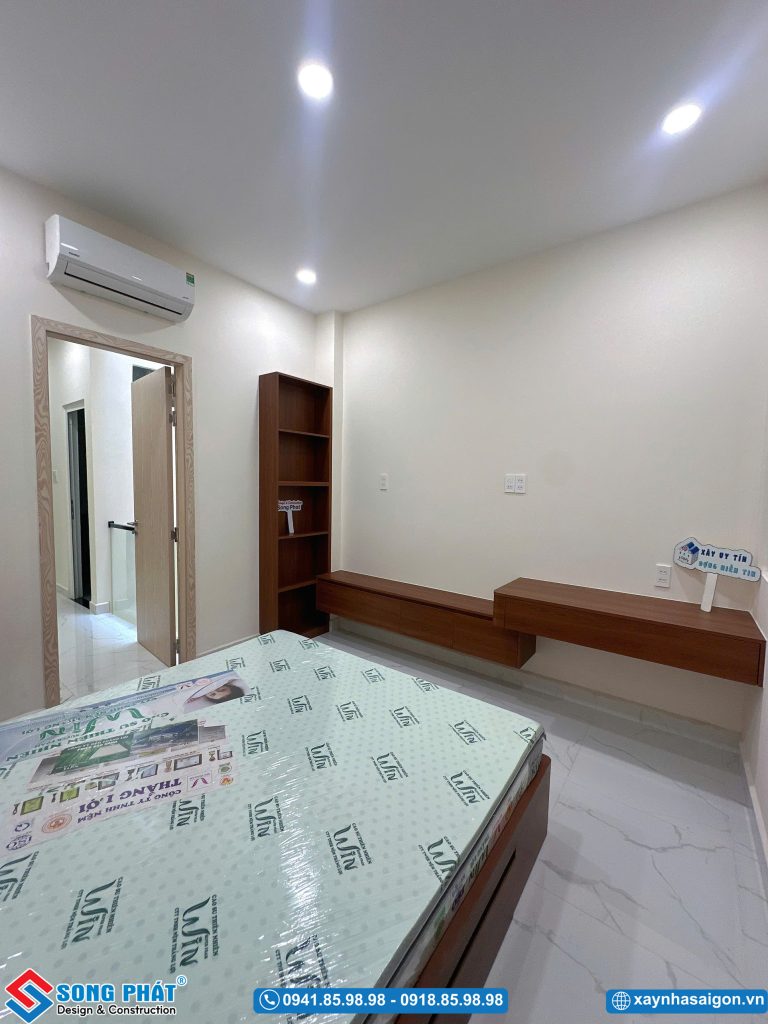 Góc nhìn hướng về cửa ra vào, tích hợp kệ sách đứng và kệ treo tường gọn gàng.