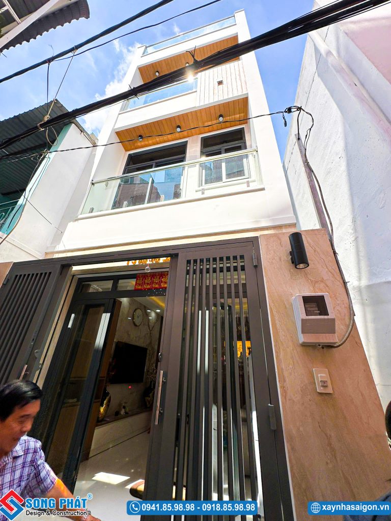 Mặt tiền nhà phố 3 tầng hiện đại với ban công kính và trần ốp gỗ.