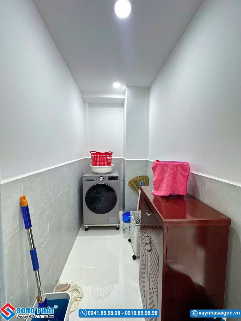 Khu vực giặt phơi nhỏ gọn bố trí máy giặt và tủ đựng dụng cụ vệ sinh.