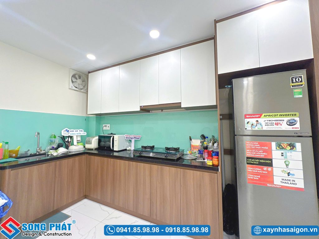 : Không gian phòng bếp gọn gàng, tiện nghi với tủ bếp trên dưới và tủ lạnh lớn.