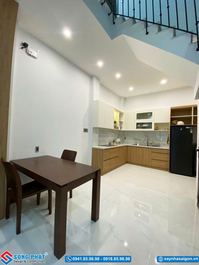 Không gian bếp bố trí gọn gàng với tủ bếp chữ L và bộ bàn ăn nhỏ gọn phía trước.