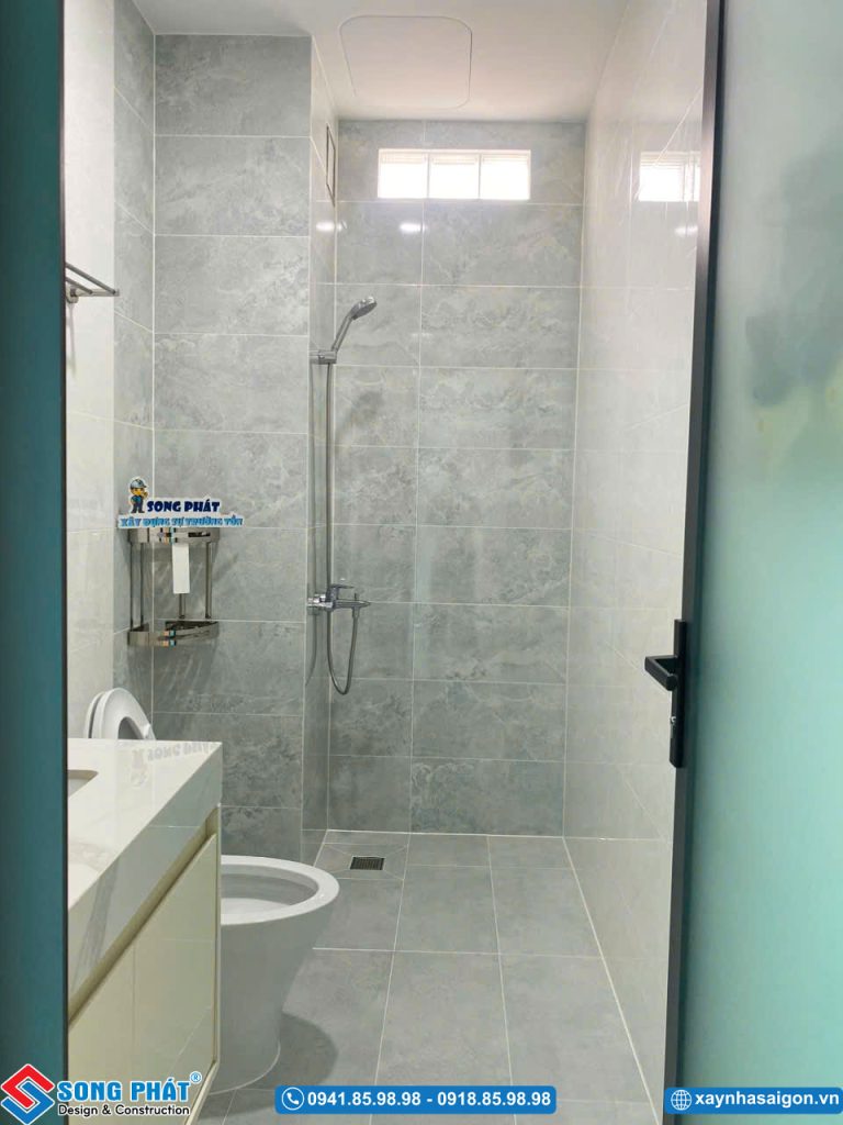  Phòng tắm nhỏ gọn với tông màu xám sáng và các thiết bị vệ sinh đầy đủ.   