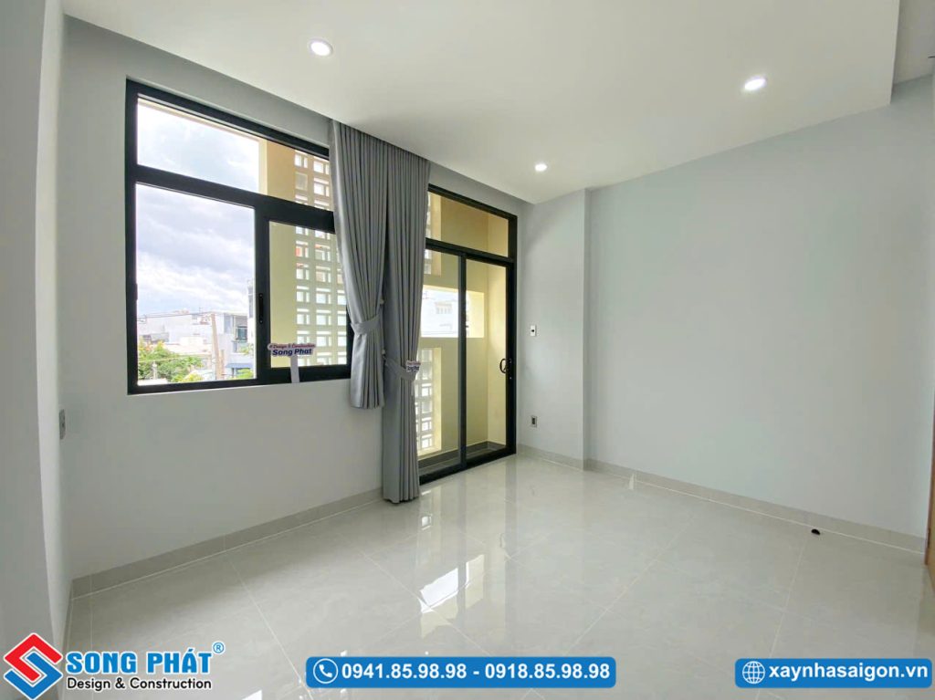 Góc nhìn từ trong phòng ra hướng cửa kính khung nhôm xám kết hợp rèm rủ tone xám tinh tế.